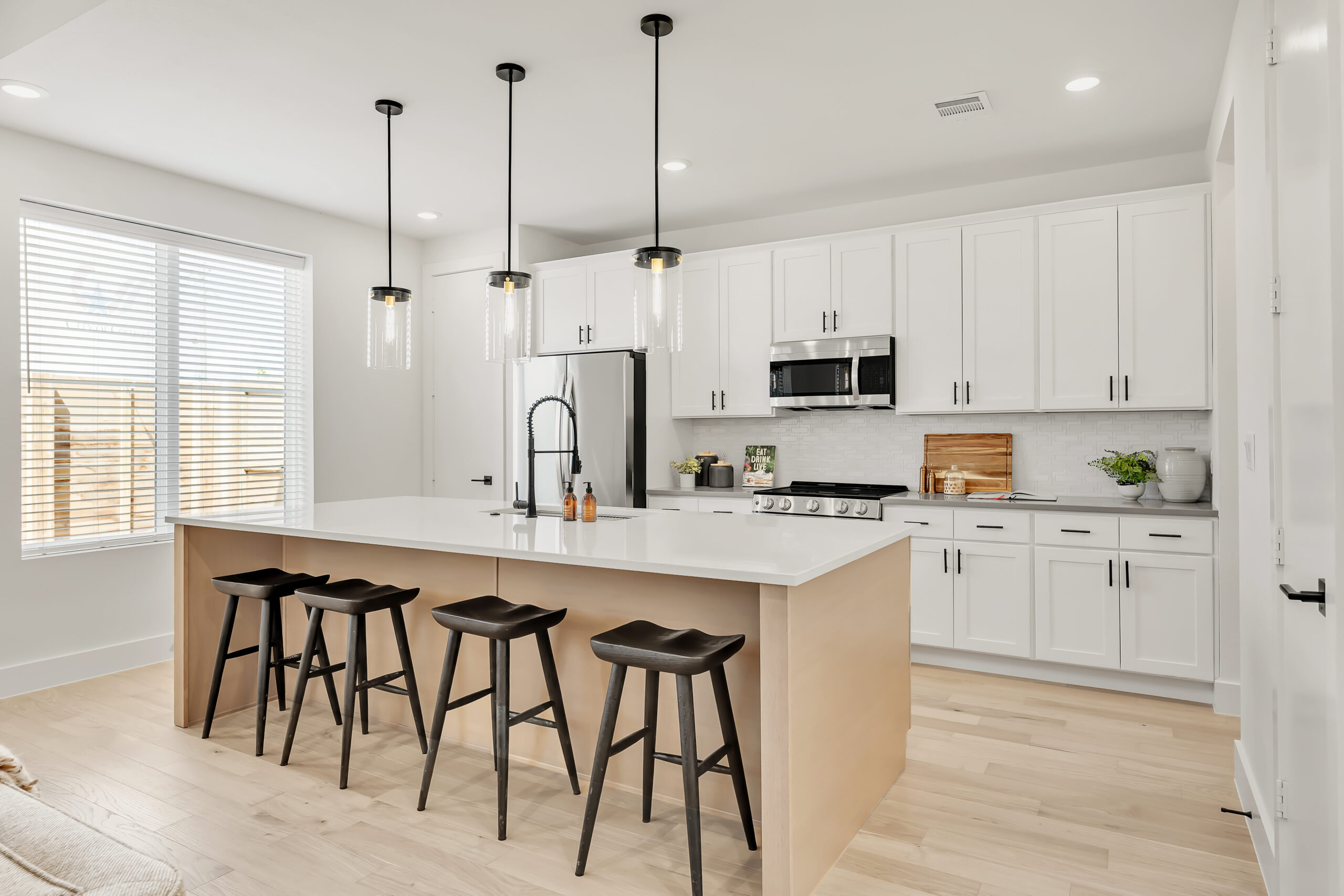 Model home kitchen with oversized quartz island, shaker cabinetry, and stainless appliances