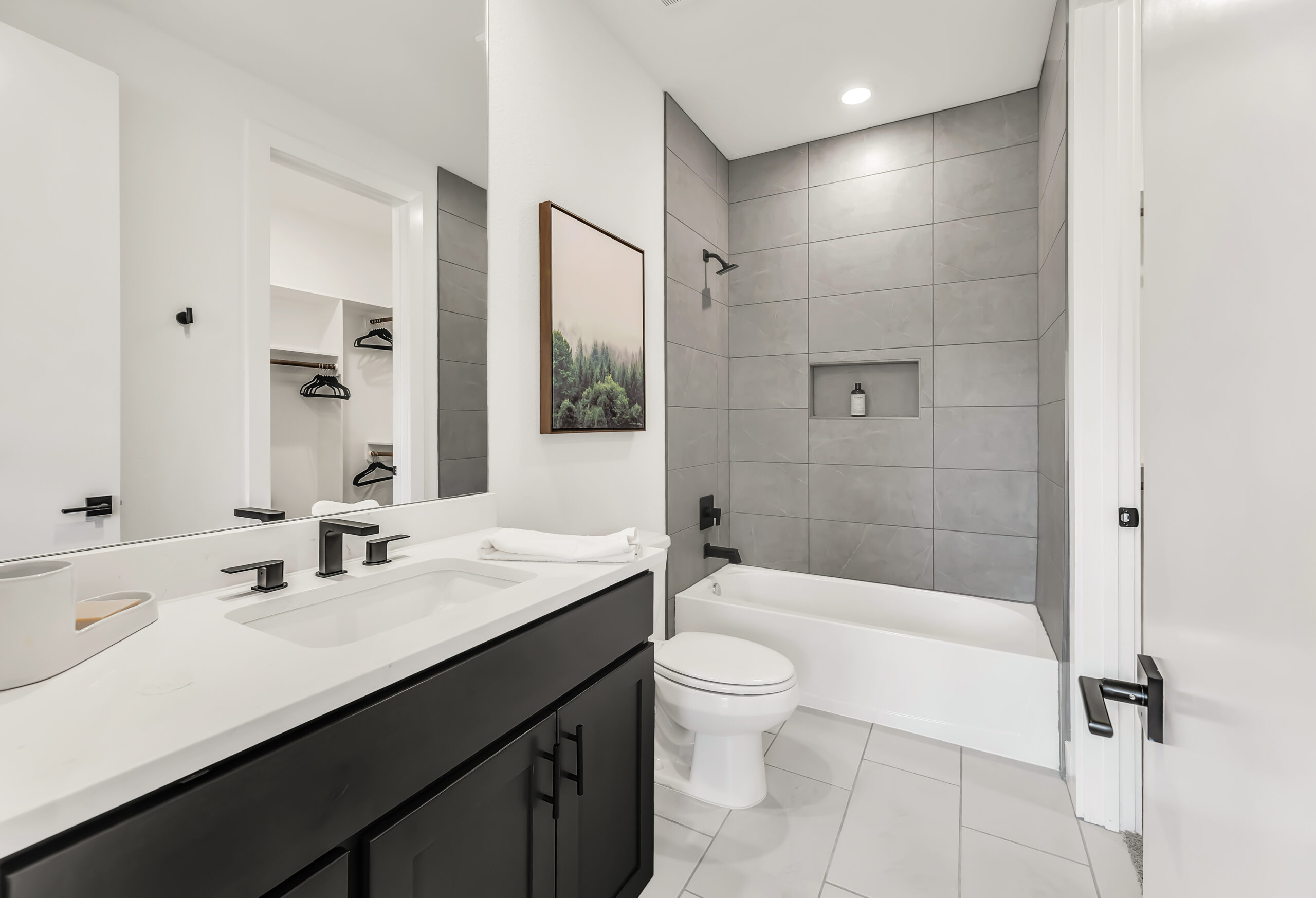 Hotel-style bathroom with ceiling-height tile and mirrors